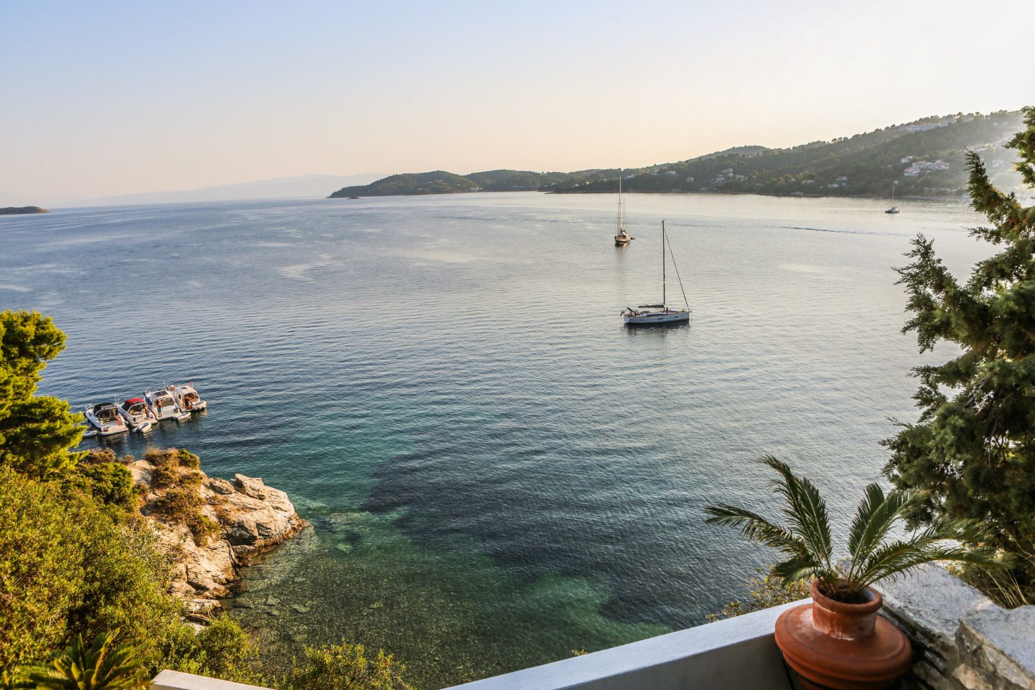 wide shot boats body water surrounded by mountains green plants skiathos greece